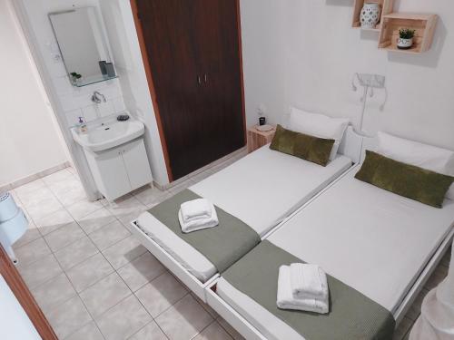 two beds in a bathroom with a sink and a mirror at Kato Yialos Paros in Parikia