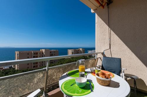 une table avec une assiette de nourriture sur un balcon dans l'établissement Chapelle des Grecs - 1km de la plage, à Ajaccio
