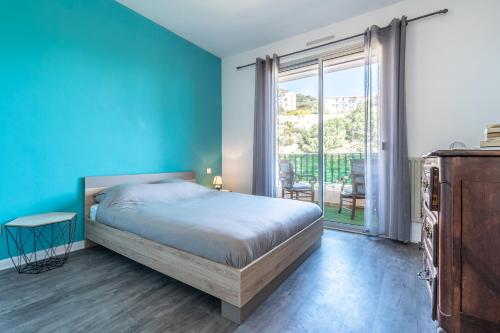 une chambre avec un lit et un mur bleu dans l'établissement Chapelle des Grecs - 1km de la plage, à Ajaccio