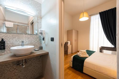 La salle de bains est pourvue d'un lavabo et d'un lit dans la chambre. dans l'établissement Duomo Hermes Relais - By Pera Rooms Collection, à Naples