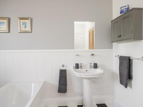 a white bathroom with a sink and a bath tub at Mill End in Penrith