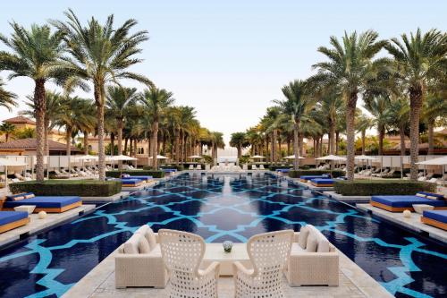 a swimming pool with chairs and palm trees at One&Only The Palm Dubai in Dubai