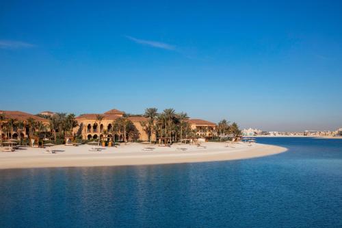 a beach with chairs and palm trees on it at One&Only The Palm Dubai in Dubai