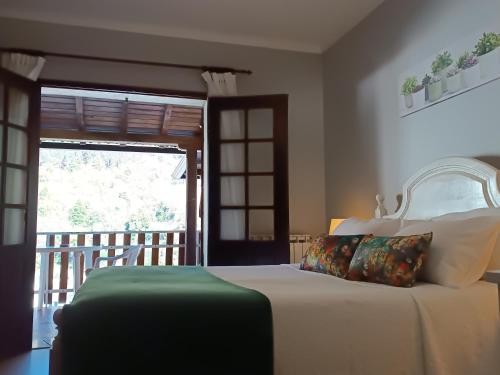 1 dormitorio con 1 cama y puerta con balcón en São Miguel do Gerês, en Gerês