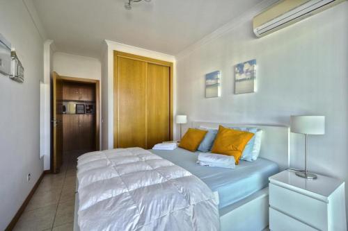 a bedroom with a large white bed with yellow pillows at Apartamento Varandas do Mar in Albufeira