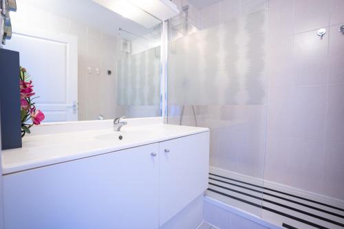 a white bathroom with a sink and a shower at Appartement clim piscine garage in Le Grau-du-Roi
