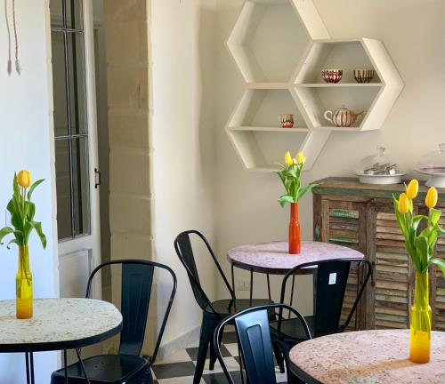 two tables and chairs with flowers in vases on them at HABITARE Lecce & Salento in Lecce