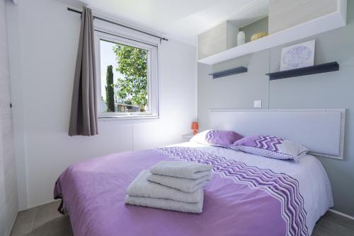 a bedroom with a purple bed with towels on it at Mobile-home 132 in Lattes