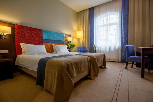 a hotel room with a large bed and a window at Młyn Jacka Hotel & Spa in Wadowice