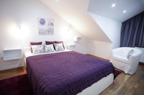 sypialnia z fioletowym łóżkiem i krzesłem w obiekcie Bonus Apartments w Zagrzebiu