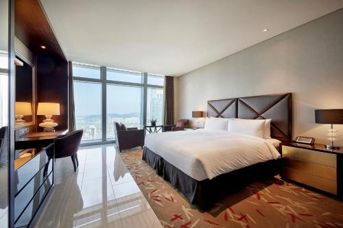 a bedroom with a bed and a desk and a large window at Oakwood Premier Incheon in Incheon