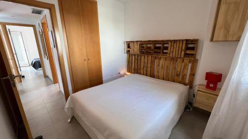 um quarto com uma cama branca e uma cabeceira em madeira em Apartamento acogedor con piscina en Santa Margarita em Roses