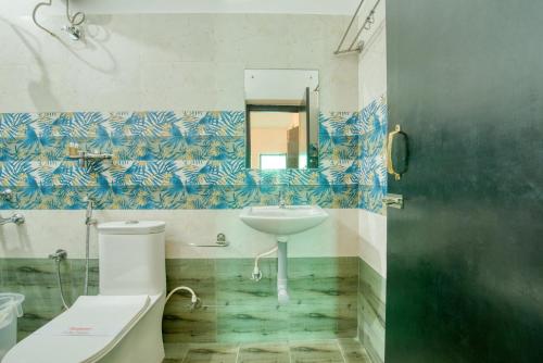 a bathroom with a sink and a toilet and a mirror at La Maison Charu in Puducherry