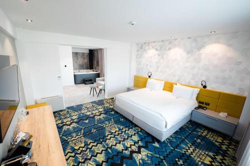 a bedroom with a white bed and a colorful carpet at Mandachi Hotel & SPA in Suceava