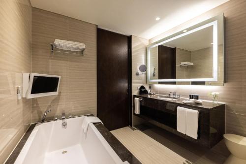 a bathroom with a tub and a sink and a mirror at Oakwood Premier Incheon in Incheon