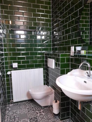 a green tiled bathroom with a sink and a toilet at Hotel Bed & Breakfast De Poffert in Borger