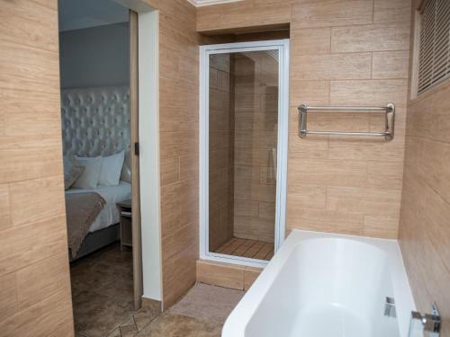 a bathroom with a bath tub and a bedroom at Barkly Street Guesthouse in Uitenhage