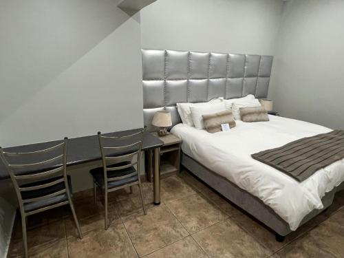 a bedroom with a bed and a table and chairs at Barkly Street Guesthouse in Uitenhage