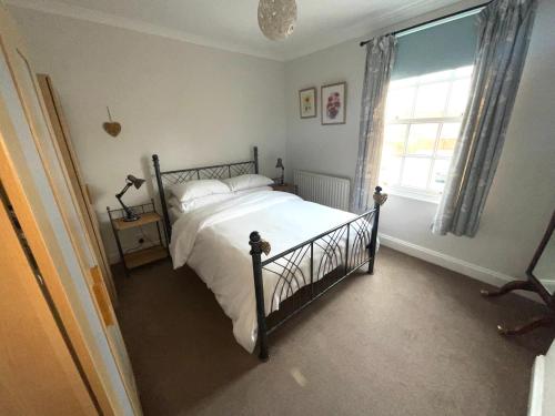 a bedroom with a bed with white sheets and a window at George Street Beverley in Beverley