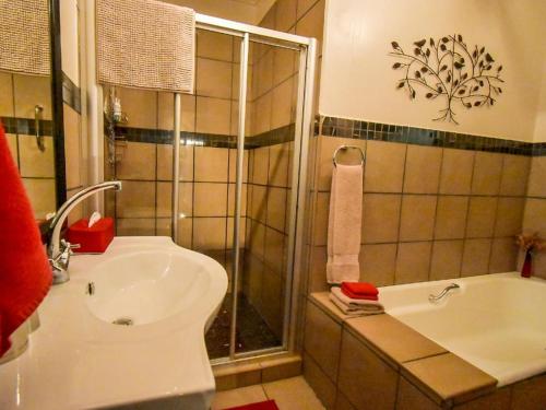 a bathroom with a shower and a sink and a tub at Rooiland Clarens in Clarens