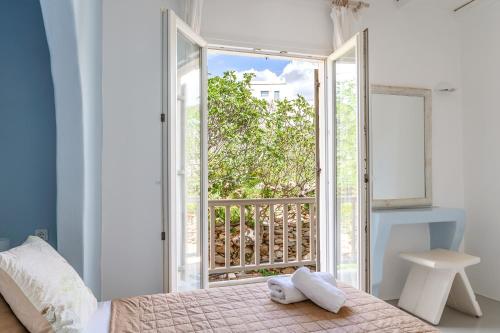a bedroom with a bed and an open door to a balcony at Ninemia Suites Tinos Grand 104 in Kionia