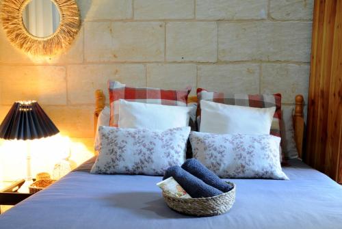 Una cama con almohadas y una cesta. en A charming and cosy townhouse in a quaint village, en Sannat