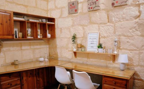a stone room with a counter with white chairs at A charming and cosy townhouse in a quaint village in Sannat