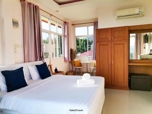 a bedroom with a large white bed and windows at Phuyafahsai The Resort Khao Kho in Khao Kho