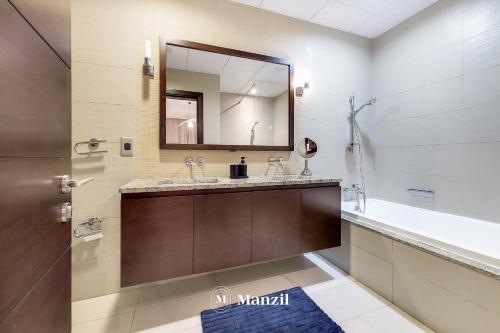 a bathroom with a sink and a mirror and a tub at Manzil - Lavish 3BR resort with private beach at Tiara Residence Palm Jumeirah in Dubai