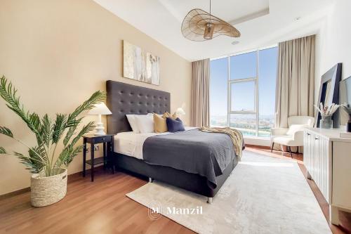 a bedroom with a bed and a large window at Manzil - Lavish 3BR resort with private beach at Tiara Residence Palm Jumeirah in Dubai