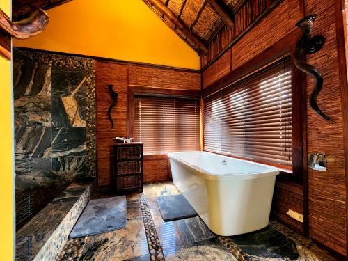 a bathroom with a large tub and wooden walls at Phumelo Lodge in Bela-Bela