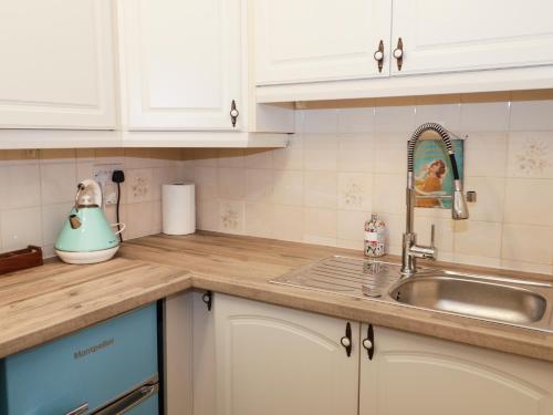 Una cocina con gabinetes blancos y un fregadero. en 50A Lloyd Street West, en Llandudno