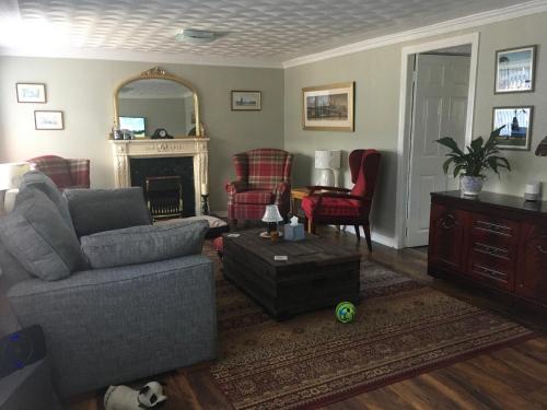 a living room with a couch and chairs and a mirror at Minton cottage in Leadhills