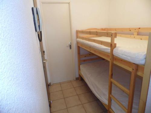 Cette chambre comprend 2 lits superposés et une porte. dans l'établissement Appartement cosy 2 pièces cabine, 2 terrasses, parking, à 140m de la plage ! - FR-1-326-538, à Marseillan