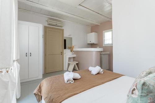 a white bedroom with two towels on a bed at Ninemia Suites Tinos Superior 101 in Kionia