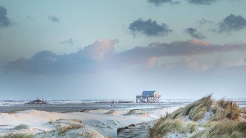 a view of the beach with a pier in the background at Zum Landhaus Norddeich in Norddeich
