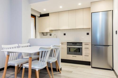 a kitchen with a white table and chairs and a refrigerator at Castrillo 4 Apartamento Acogedor in Zaragoza