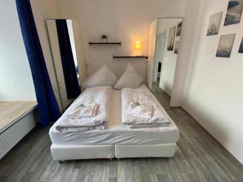 uma cama num pequeno quarto com lençóis brancos e almofadas em Apartments Osterstraße em Norden