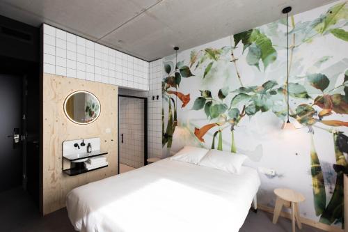 um quarto com uma cama branca e uma parede floral em hotel Moloko -just a room- sleep&shower-digital key by email-SMS em Enschede