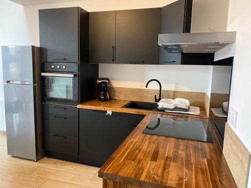 une cuisine avec des armoires noires et un comptoir en bois dans l'établissement Appartements neufs avec garages dans maison de village, à Andance