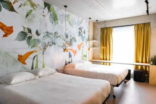 two beds in a room with a mural on the wall at the urban hotel Moloko - rooms only - unmanned - digital key by email in Enschede
