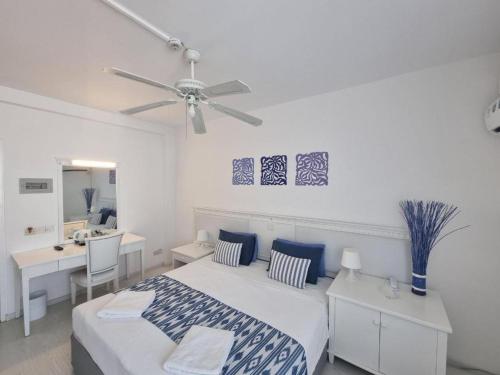 a bedroom with a bed and a desk and a ceiling fan at NEREUS HOTEL By IMH Europe Travel and Tours in Paphos City