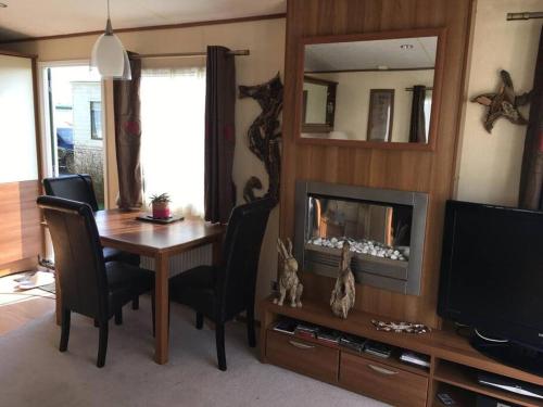 a living room with a dining room table and a television at Dymchurch Caravan Park on Romney Marsh in Dymchurch