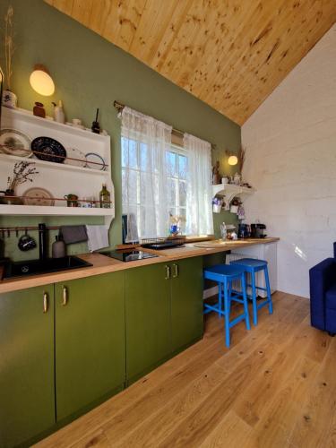 uma cozinha com armários verdes e bancos azuis em Pieninė em Ventė
