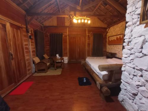 1 dormitorio con cama y pared de piedra en Nirankara Nglolang Resort, en Baron