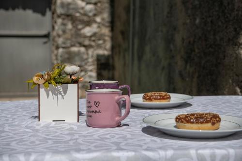 ein Tisch mit Tellern voller Donuts und einer rosa Kaffeetasse in der Unterkunft Mare Stari grad in Trebinje