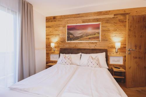 a bedroom with a white bed with a wooden wall at Chalet Molly by we rent in Zell am See
