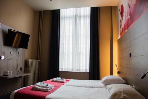 a hotel room with two beds and a window at Hotel Industrie in Leuven
