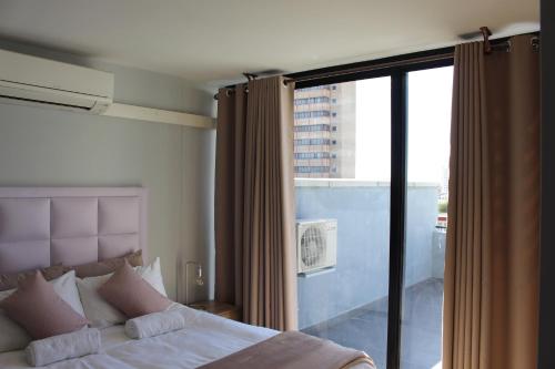 a bedroom with a bed and a large glass window at Home away from Home in Windhoek