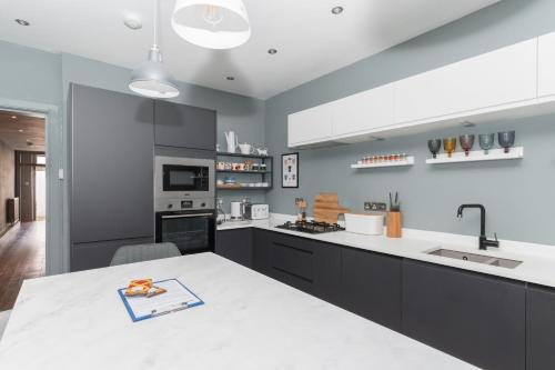 - une cuisine avec un comptoir blanc et un évier dans l'établissement Beautiful & Bright 2BD Flat - Haymarket, à Édimbourg